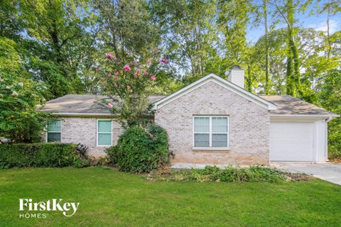 a small brick house with a lawn and a white garage