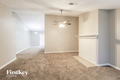 an empty living room with a ceiling fan