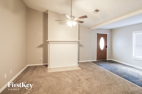 a empty living room with a ceiling fan and a door