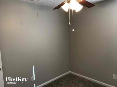 a living room with a ceiling fan and a gray wall