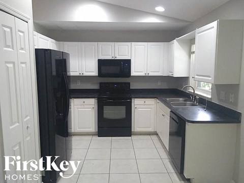 A kitchen with black appliances and white cabinets.