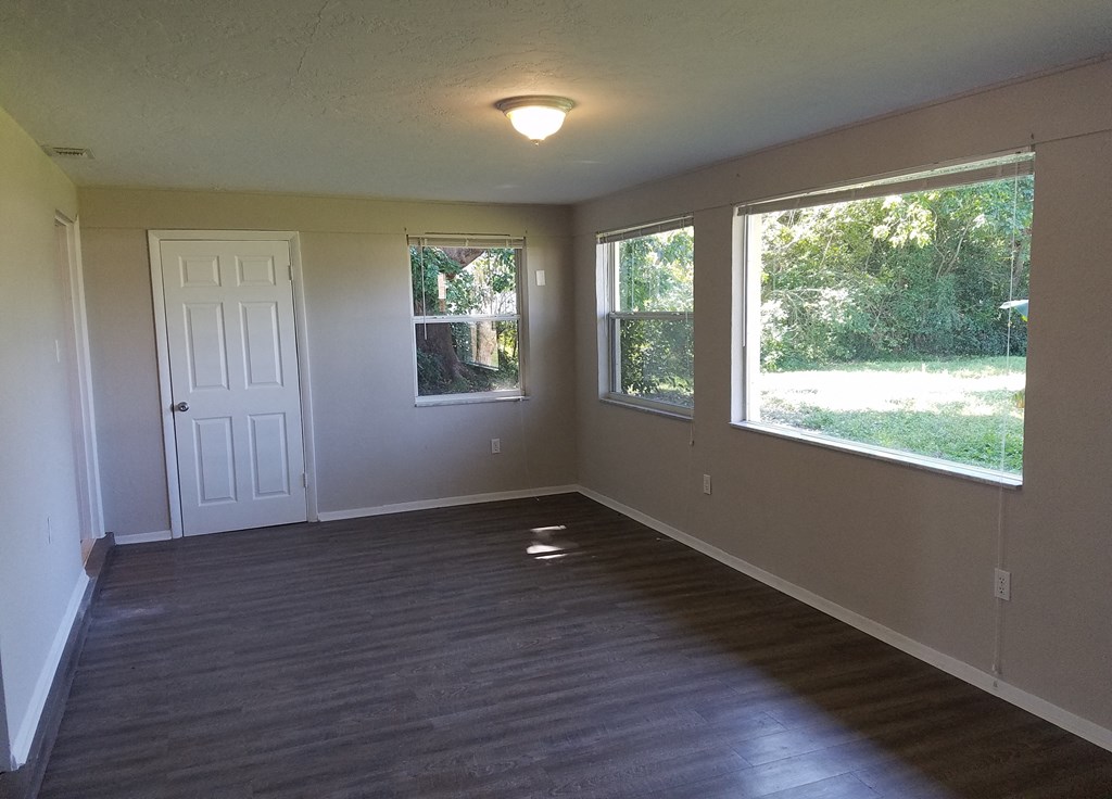 an empty living room with a wooden floor and large windows