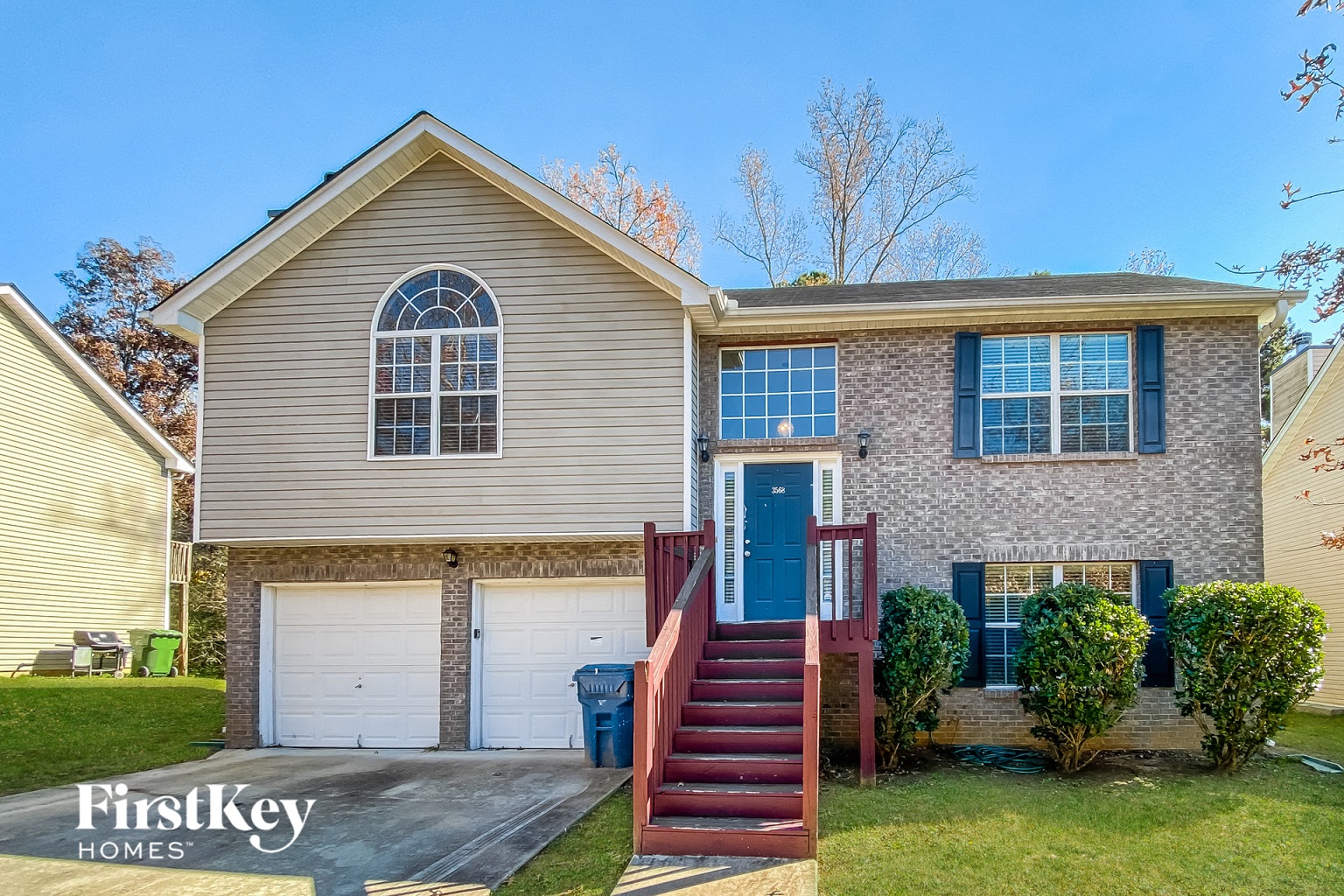 a tan house with a blue door and red stairs