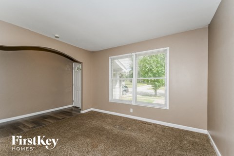 a bedroom with a large window and a carpeted floor
