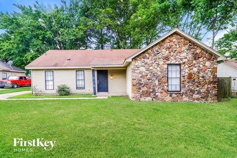 a small house with a stone facade and a grassy yard