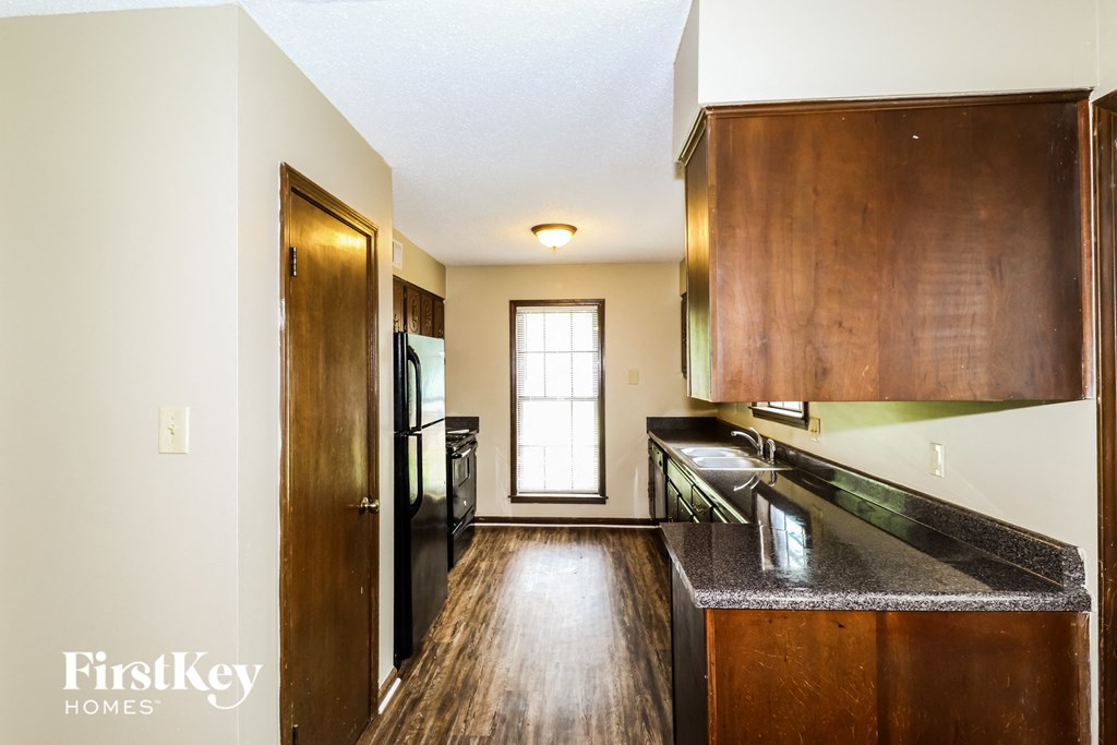 a kitchen with wooden cabinets and a black counter top