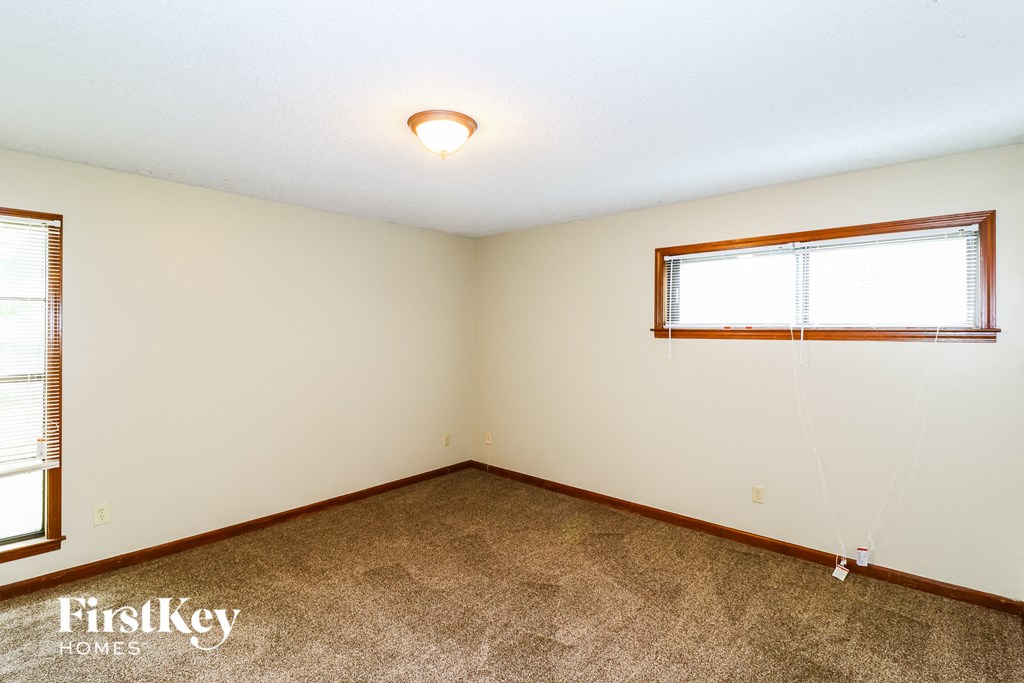 the living room of a house with carpet and a window