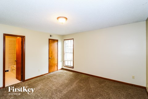 the master bedroom with carpeted flooring and a door to the bathroom