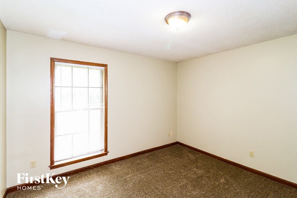 a bedroom with a window and a carpeted floor