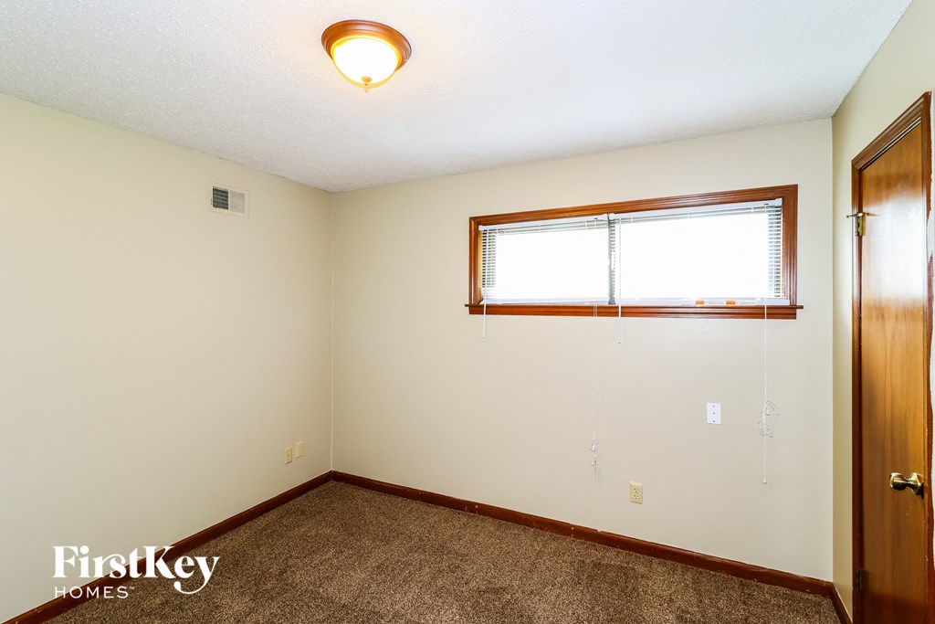 a bedroom with a window and a carpeted floor
