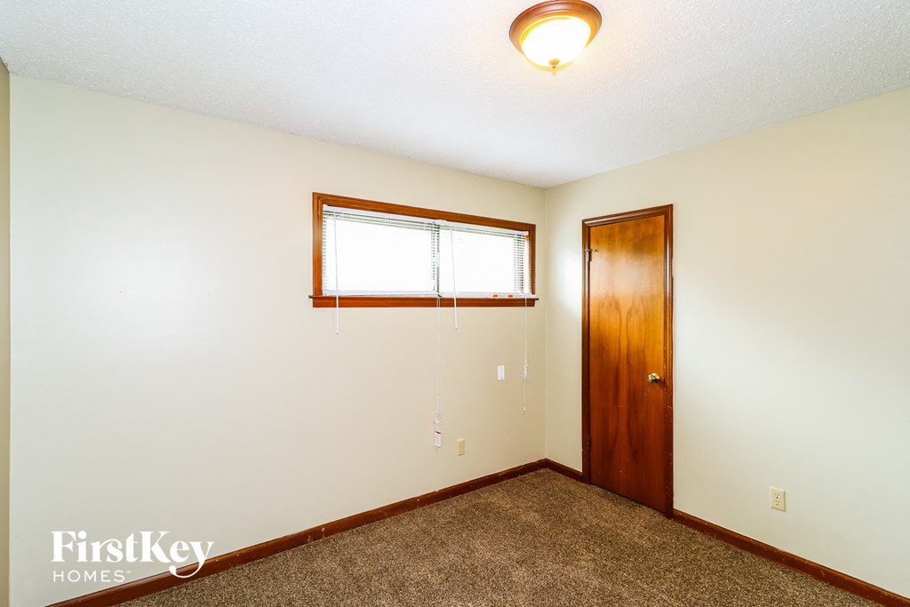 a bedroom with white walls and a wooden door and a window