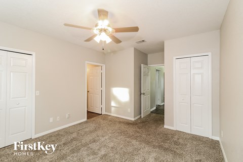 a spacious living room with carpet and a ceiling fan