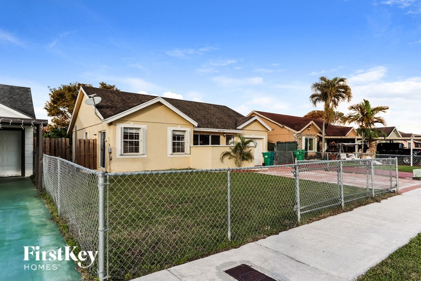 a house with a tennis court in front of a chain link fence