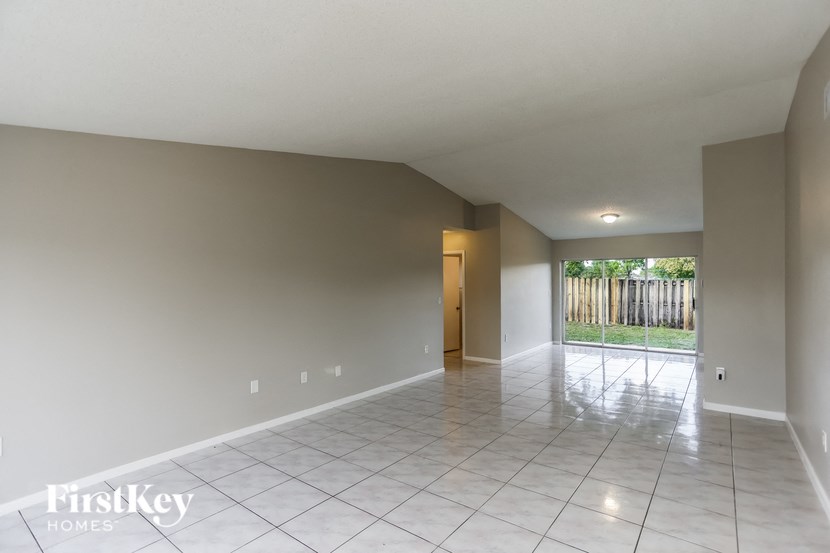 a large empty living room with a tiled floor and a sliding glass door
