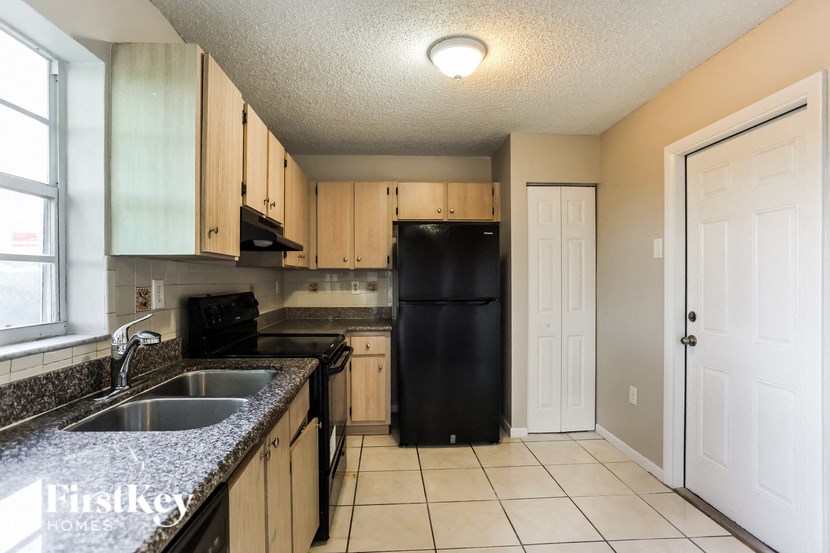 a kitchen with a sink and a black refrigerator