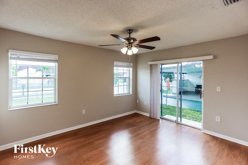 an empty living room with wood floors and a ceiling fan