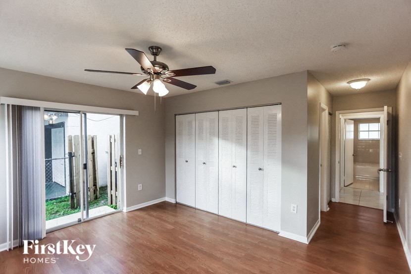 an empty living room with a ceiling fan and a closet