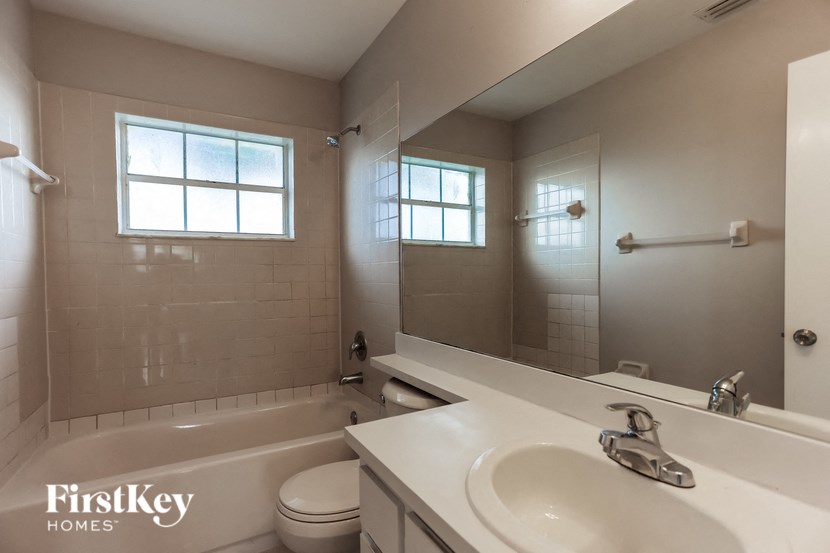 a white bathroom with a sink and a tub and a mirror