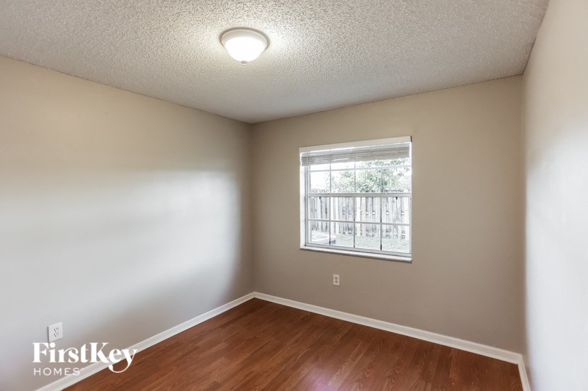 a bedroom with wood flooring and a window