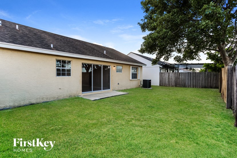 a backyard with a white house and a yard and a tree