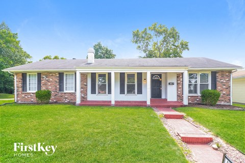 a small brick house with a lawn and a porch