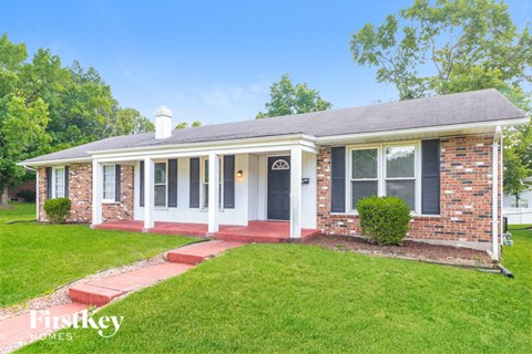 a small brick house with a porch and a lawn