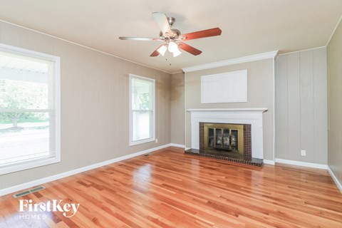 an empty living room with a fireplace and a ceiling fan