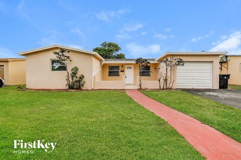 a beige house with a driveway and a lawn