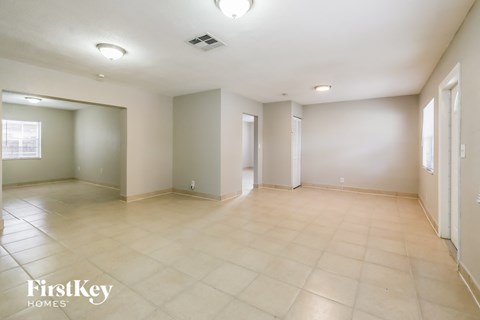 a spacious living room with beige tile floors and white walls