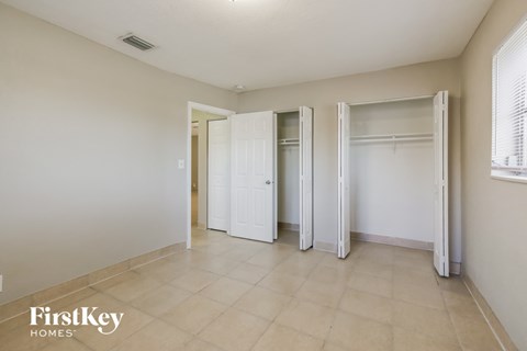 a bedroom with three closets and a tiled floor and white doors
