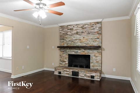 the living room has a stone fireplace and hardwood floors