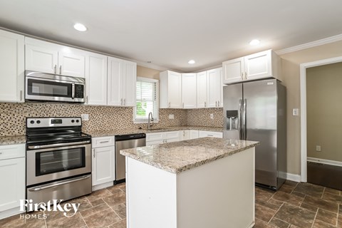 a white kitchen with stainless steel appliances and a granite counter top