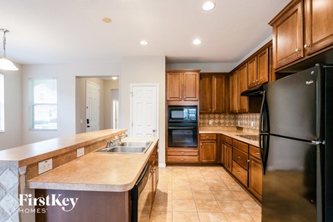 A kitchen with wooden cabinets and a black refrigerator.