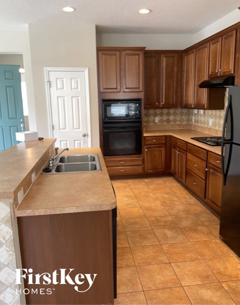 A kitchen with brown cabinets and a black refrigerator.