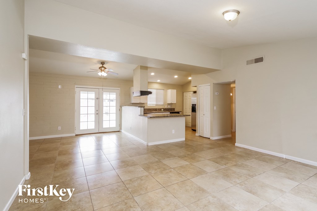 an open kitchen and living room with tile flooring and a ceiling fan