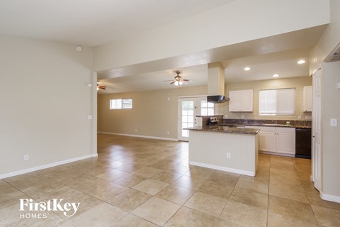 an open kitchen and living room with white cabinets and tile flooring