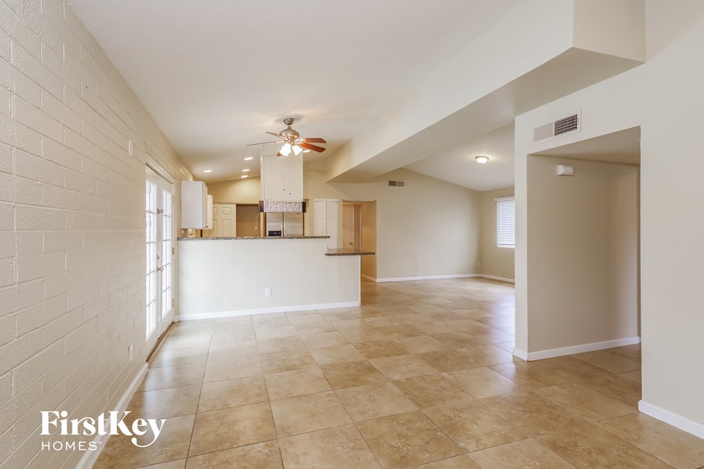 an open kitchen and living room with tile floors and a ceiling fan