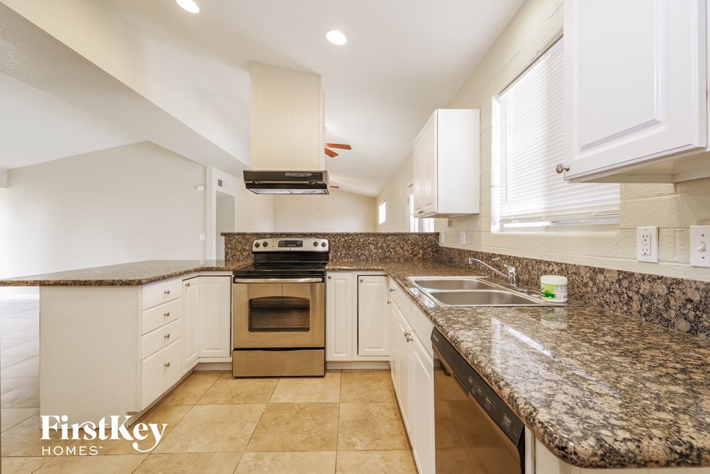 a kitchen with granite counter tops and white cabinets and a sink