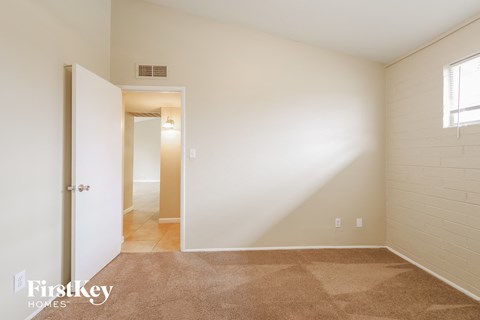 a bedroom with white walls and carpet and a door to a hallway