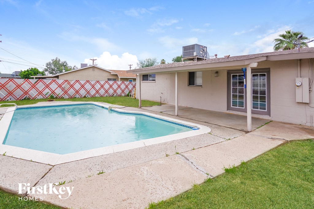 a backyard pool and a house with a yard and a white fence