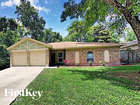 a small brick house with a yard and a garage