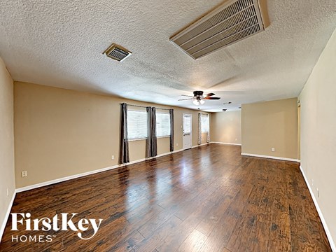 an empty living room with wood floors and a ceiling fan