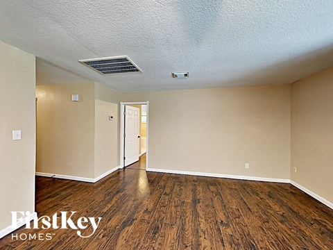 an empty living room with wood flooring and white walls