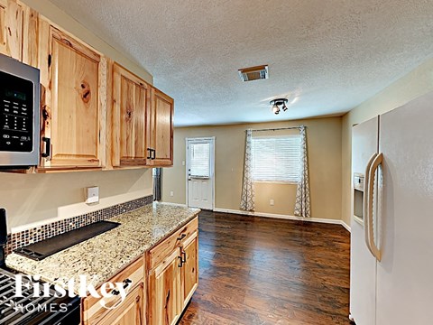 an empty kitchen with wood cabinets and granite counter tops