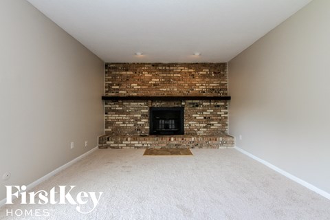 a large empty living room with a brick fireplace