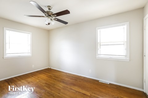 a bedroom with wood floors and a ceiling fan