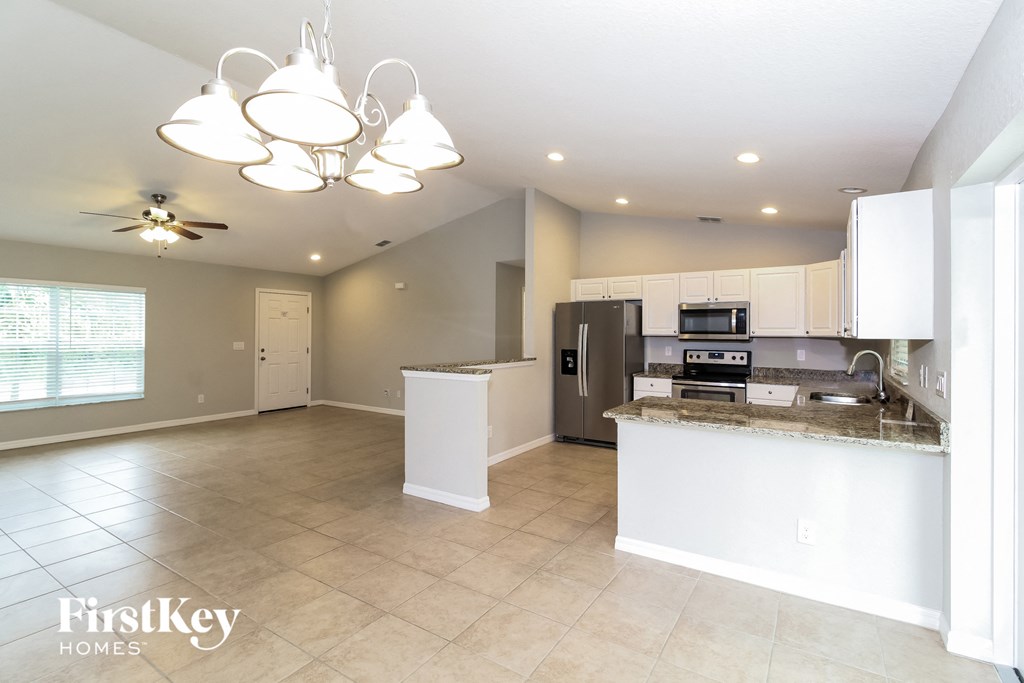 an open kitchen and living room with white cabinets and stainless steel appliances