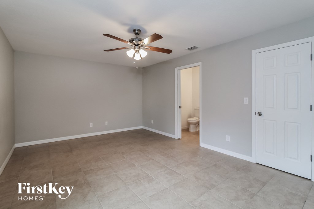 the master bedroom has a tile floor and a ceiling fan