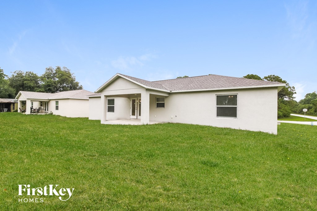 a white house on a hill with a grassy yard