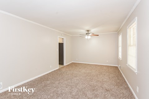 a spacious living room with carpet and a ceiling fan